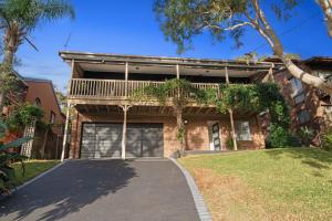 a driveway leading to a brick house with a balcony at Flannel Flower Beach House in Shoal Bay