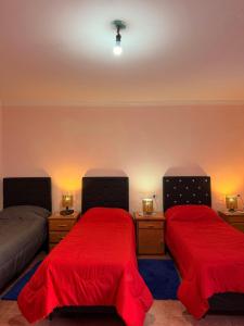 a bedroom with two beds with red covers and lights at Duna Blanca I in Fiambalá +1 photo