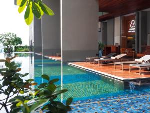 a swimming pool in a building with chairs and tables at Hansar Bangkok Hotel in Bangkok