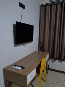 a room with a table and a television on a wall at Flat luxo e tranquilidade in Volta Redonda
