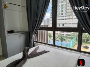 a bed with a snake laying on it in front of a window at Bali Residence Melaka By Heystay Management in Malacca