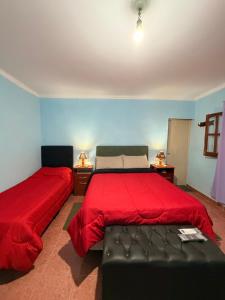 a bedroom with two beds with red sheets and a couch at Duna Blanca II in Fiambalá