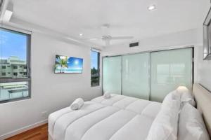 a large white bed in a room with windows at Picnic Point Panoramic Views in Maroochydore