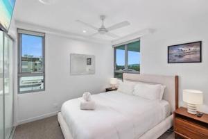 a white bedroom with a white bed and windows at Picnic Point Panoramic Views in Maroochydore +13 photos