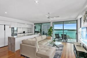 a living room with a couch and a kitchen at Picnic Point Panoramic Views in Maroochydore