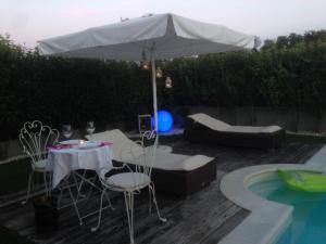 un tavolo e sedie sotto un ombrellone accanto alla piscina di Sonomusica B&B a Gazzola Di Rivalta