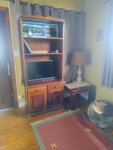 a living room with a tv on a wooden entertainment center at casa charme e praticidade in Campos do Jordão