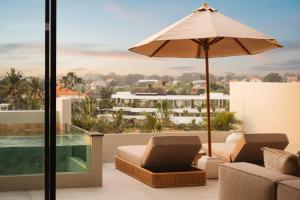 a patio with an umbrella and a couch and chairs at Sore Escape Tumbak Bayuh by Betterplace in Canggu