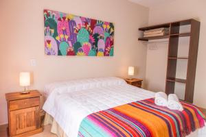 Las Tulmas Apartamentos Salta في سالتا: غرفة نوم بسرير ودهان على الحائط