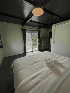 a bedroom with a large white bed with a window at เหนือสะปัน in Ban Huai Ti