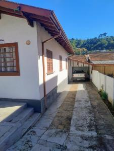 a white house with a car parked in a driveway at casa charme e praticidade in Campos do Jordão