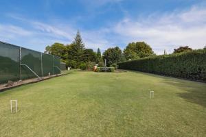 a large grassy field with a fence and trees at The Raukawa Cottage in Tauranga +17 photos