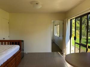 a bedroom with a bed and a table and windows at The Raukawa Cottage in Tauranga