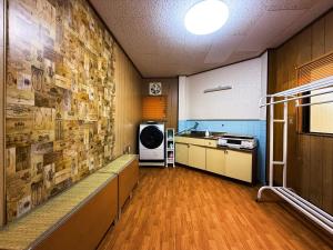 a room with a kitchen with a wall covered in pictures at Ema-長吉 in Osaka