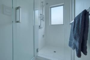 a white bathroom with a shower and a window at Fern View - Cozy 2-bedroom house in Hokitika +17 photos