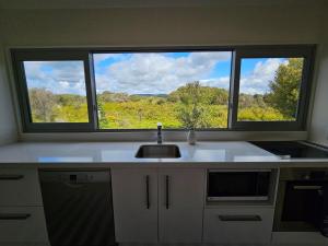 a kitchen with a sink and two large windows at Fern View - Cozy 2-bedroom house in Hokitika