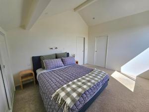 a bedroom with a large bed with purple pillows at Fern View - Cozy 2-bedroom house in Hokitika