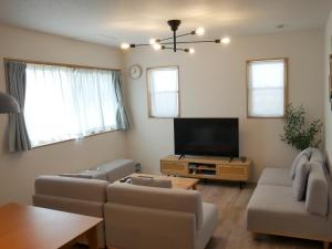 ein Wohnzimmer mit Sofas und einem Flachbildfernseher in der Unterkunft アオイカゼ in Awaji