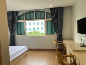 a bedroom with a large window with a bed and a desk at Emerald Marina TL in Phú Quốc