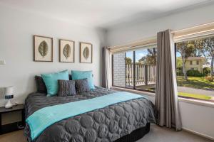 a bedroom with a large bed and a window at Mollymook Beach Haven - near ocean & golf course in Mollymook
