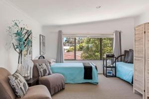 a bedroom with a bed and a couch and a window at Mollymook Beach Haven - near ocean & golf course in Mollymook +12 photos