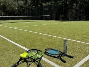 two tennis rackets and balls on a tennis court at Fathoms 5 - 2BR beach resort apartment in Mollymook