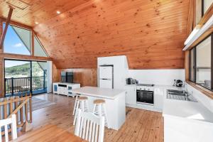 a kitchen with white appliances and wood ceilings at Sea-renity in Kioloa