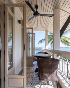 a porch with a ceiling fan and a table and chairs at B House Samui in Bangrak Beach