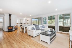 a living room with a white couch and a fireplace at The Salty Deck in Narrawallee