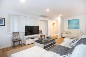 a living room with a white couch and a flat screen tv at The Salty Deck in Narrawallee