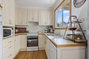 a white kitchen with white cabinets and a window at Jillby's House - 3 BR home near Narrawallee Beach in Narrawallee