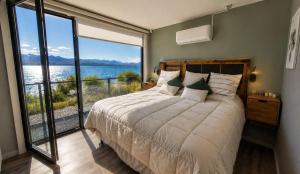 a bedroom with a bed with a view of the water at Lakefront, Jacuzzi and Pool in San Carlos de Bariloche +32 photos