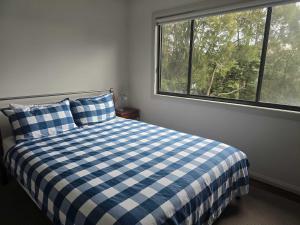 a bedroom with a blue and white checkered bed with a window at Bawley Backyard Haven - family retreat near beach in Bawley Point