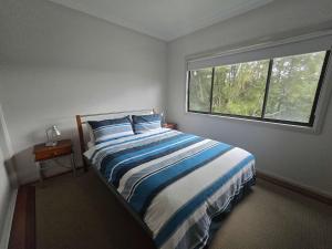 a bedroom with a large bed and a window at Bawley Backyard Haven - family retreat near beach in Bawley Point +14 photos