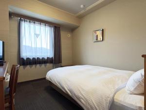 a hotel room with a bed and a window at Hotel Route-Inn Suwa Inter in Suwa +25 photos