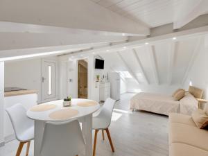 a white room with a bed and a table and chairs at Brand new attic studio apartment, air conditioned in Castelsardo