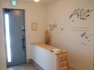 ein Zimmer mit einer Wand, an der ein Schreibtisch steht, und einer Tür in der Unterkunft アオイカゼ in Awaji