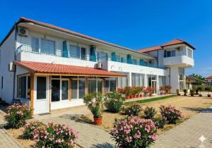 a large white building with flowers in a courtyard at Sani Family Hotel in Byala
