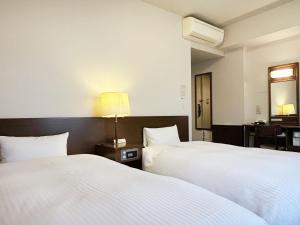 a hotel room with two beds and a desk at Hotel Route-Inn Dai-ni Suwa Inter in Suwa