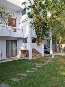 a white house with a tree in the yard at Sky Glow Residence in Pepiliyana