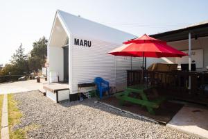 a patio with a red umbrella and a picnic table at Yeosu Maru Pension in Yeosu