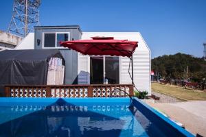 a red umbrella next to a house with a pool at Yeosu Maru Pension in Yeosu +25 photos