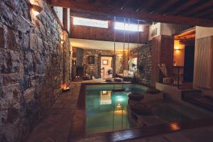 a swimming pool in a room with a stone wall at Ancient Monastery In The Lariani Mountains in Cernobbio