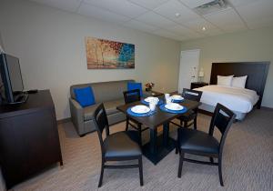 Wasaga Riverdocks Hotel Suites في واساغا بيتش: غرفة فندقية بسرير وطاولة وكراسي