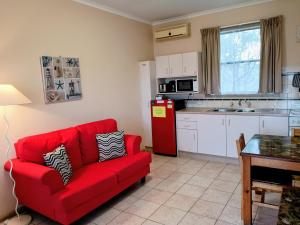 a red couch in a kitchen with a red refrigerator at Lakes Entrance Holiday Units in Lakes Entrance