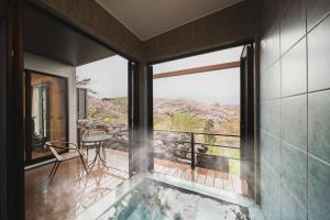 a room with a tub and a balcony with a table at 湯宿 蒼の月 in Oita