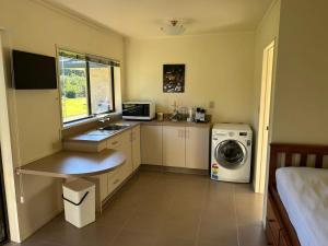 a small kitchen with a sink and a washing machine at The Raukawa Cottage in Tauranga