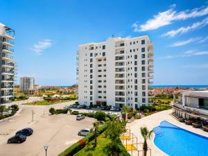 a large white building with a parking lot and a pool at Caesar Blue Collection Nothern Cyprus Family Bedroom Suites in Ayios Dhometios