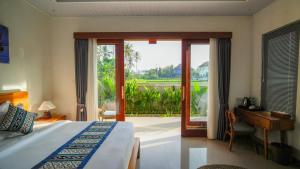 a bedroom with a bed and a desk and a window at Bale Sidi House Ubud in Ubud