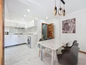 a white kitchen with a dining table and chairs at Les Sables Roses Appartement in Flic-en-Flac